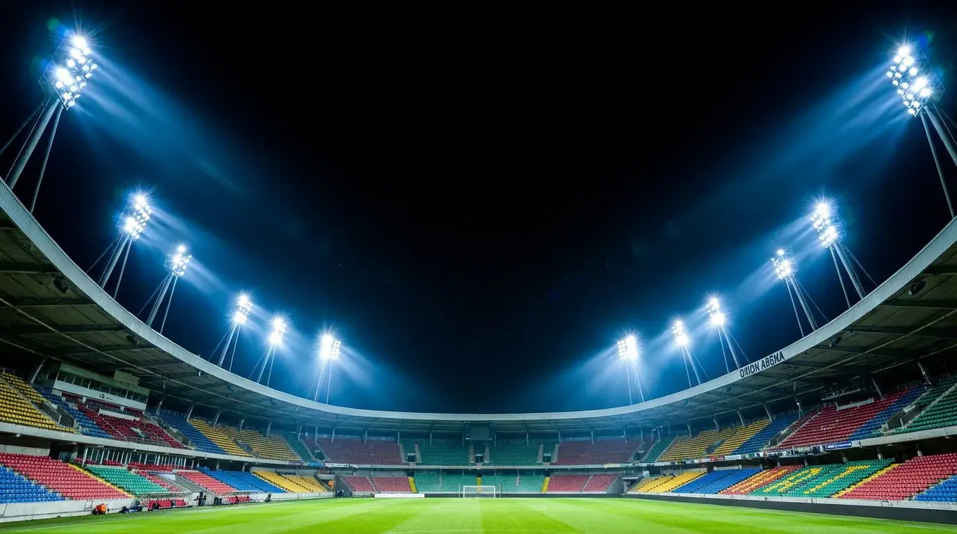 Stade de football illuminé de nuit avec projecteurs et pelouse verte
